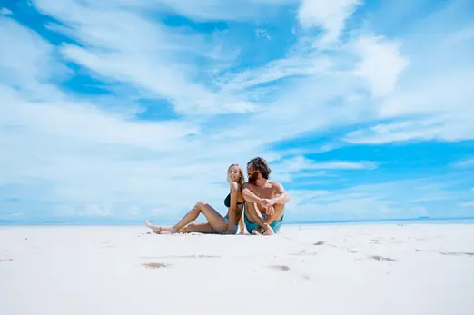 Pareja relajándose en una playa de arena blanca